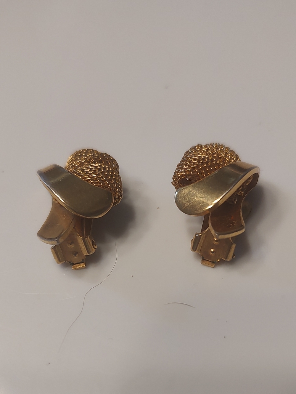 vintage gold-tone clip-on earrings featuring a textured mesh knot design, hinge